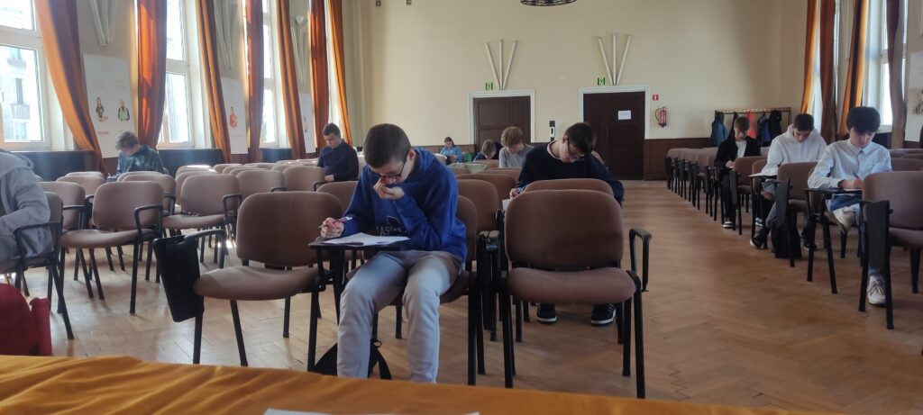 uczeń siedzący przy ławce piszący konkursowy test