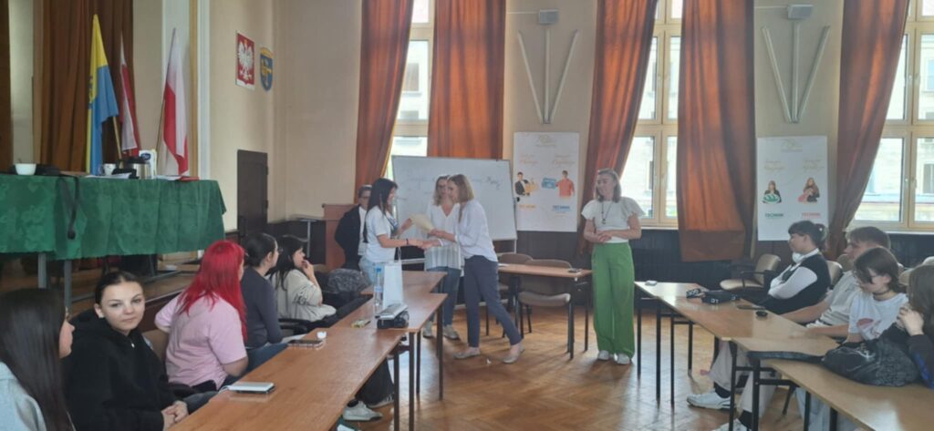 aula szkoły, w niej uczniowie wykonujący rysunki o tematyce stop przemocy, ujęcie z organizatorami
