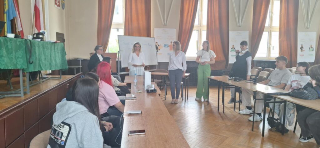 aula szkoły, w niej uczniowie wykonujący rysunki o tematyce stop przemocy, ujęcie z organizatorami
