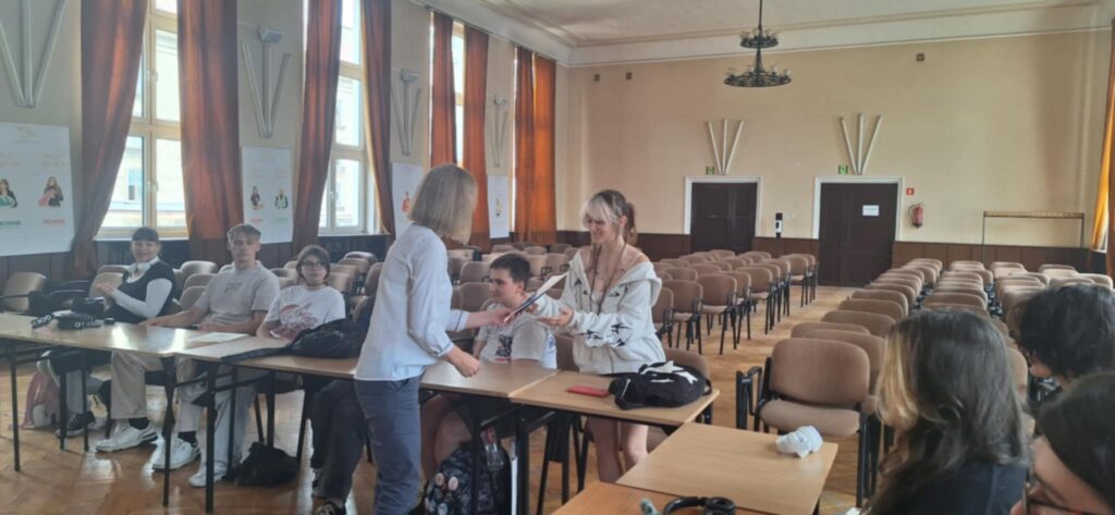 aula szkoły, w niej uczniowie wykonujący rysunki o tematyce stop przemocy